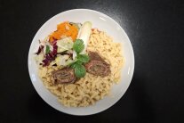 Teller mit Rindersoulade auf Spätzle an Blatt- und Karottensalat