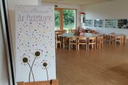 Auf einer großen Leinwand steht vor dem Speisesaal Gasthaus Zur Pusteblume