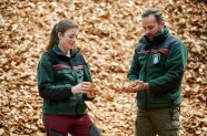 Eine Frau und ein Mann, in der Uniform der bayrischen Forstverwaltung, prüfen Hackschnitzel