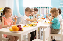 Gruppe von Kindern isst am Tisch in Kindertageseinrichtung. 